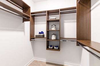 A walk in closet with wooden shelves and white walls